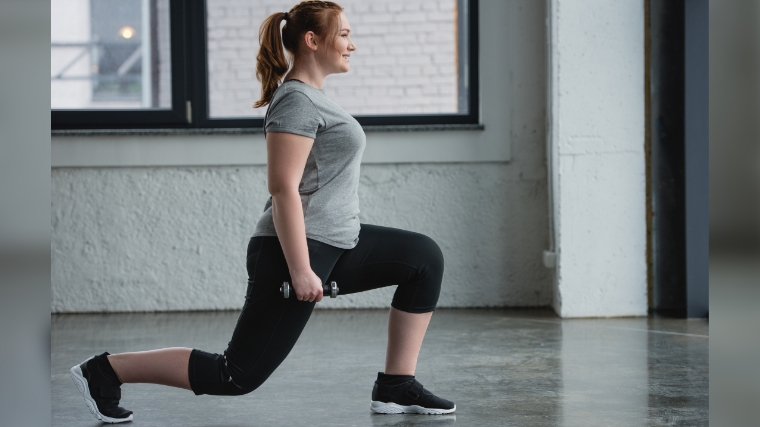 Person gray shirt performing lunges small barbell