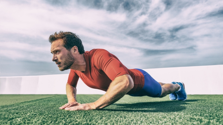 Person wearing a red shirt doing a diamond push up with the gray sky as the background.