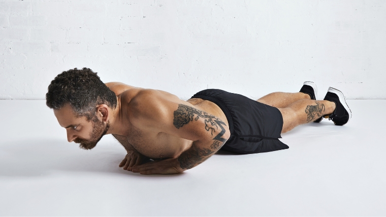 Ripped athlete with their chest touching their hands for a diamond push-up.