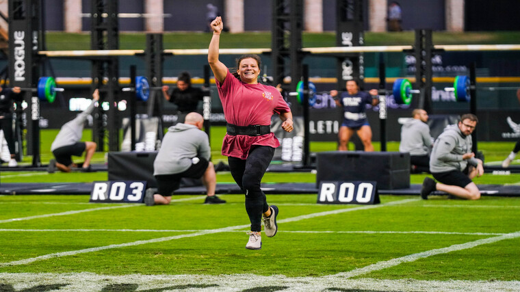 Laura Horvath raises her hand up in victory and smiles.