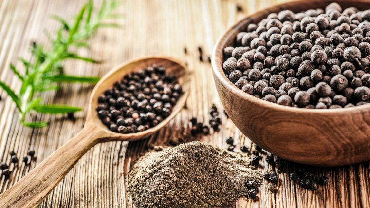 Two wooden bowls of black pepper sit on a table.