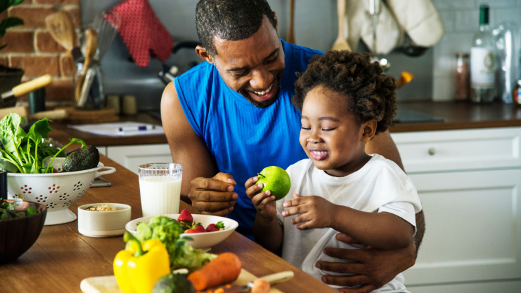 Man helps child pick healthy food after workout at home