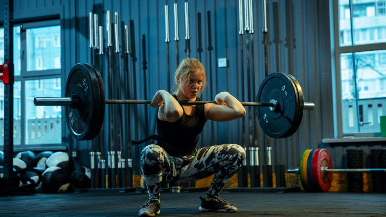 A person performs a barbell front squat in the gym.