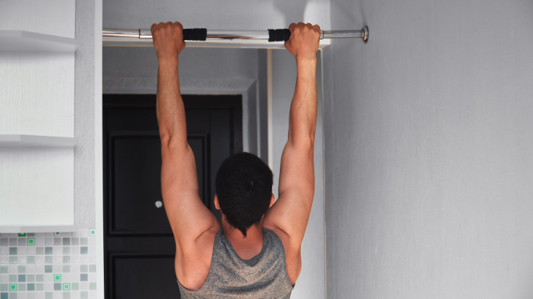 Man hangs from pull-up bar at home