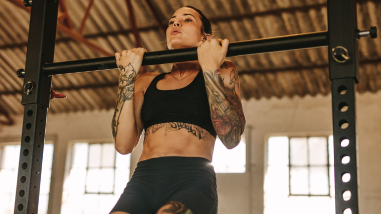 A woman performs pull-ups in a garage gym 