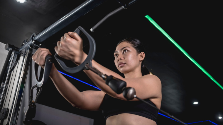 Woman performs low cable flye in gym