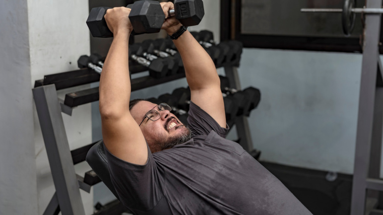 Man squeezes dumbbells at the top of flye exercise