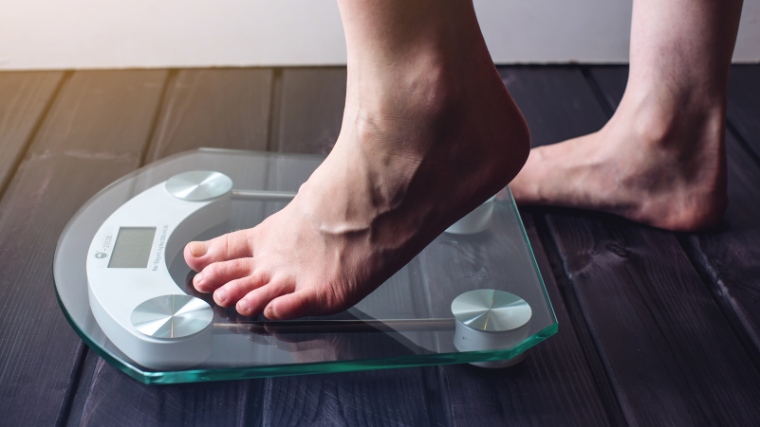 A person steps onto a scale to assess weight