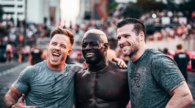A photograph of three crossfitters — Noah Ohlsen, Chandler Smith, and Travis Mayer — placing their arms around each other's shoulders and smiling.