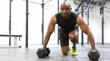 A person working out with dumbbells to help bust the physique plateau.