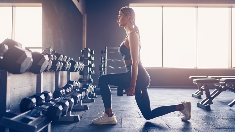 A person doing a split squat in the gym.