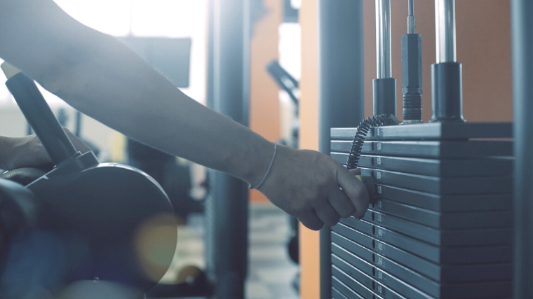 A person selecting weight on the lat pulldown machine.