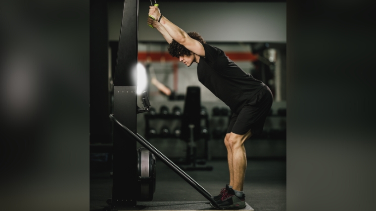 A person with arms up using a ski erg machine.