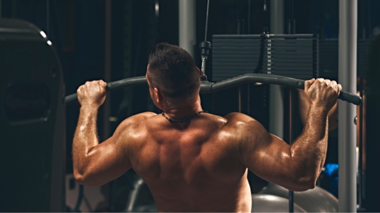 Barbend.com: Article Image: 760x427 A person working on a lat pulldown machine and shows engaged muscles.