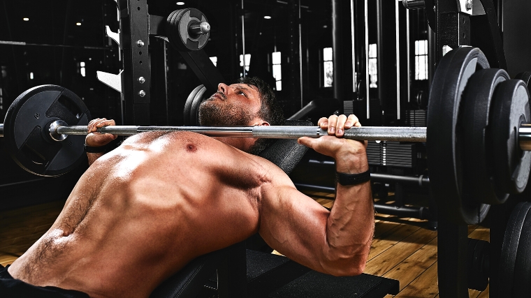 Shirtless person on the bench press in the gym.