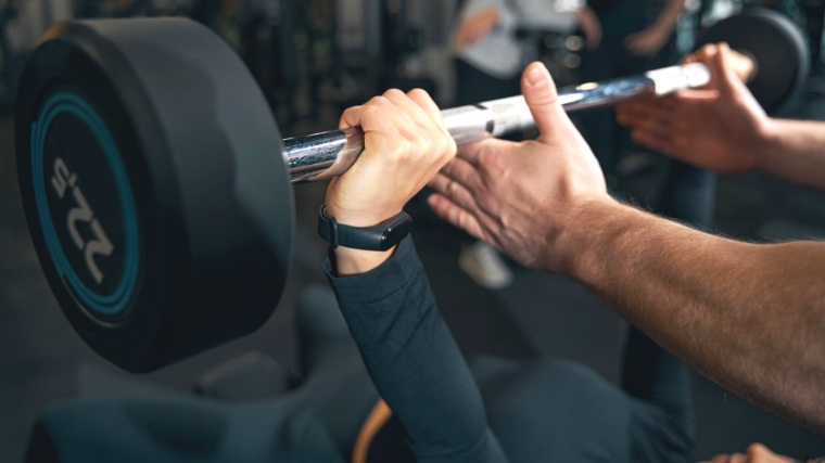 A close up of a barbell that a person is using in a bench press.