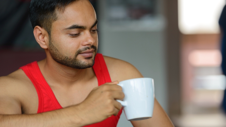 A person in workout clothes drinking coffee.