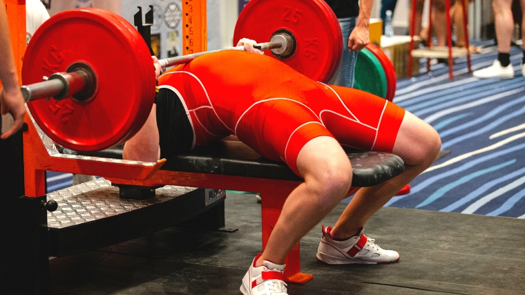 A person is doing a bench press with the barbell to his chest and back arched.