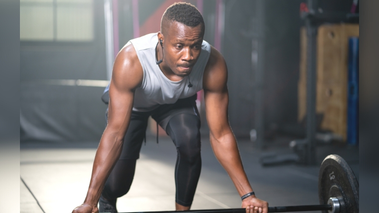 A person lifting a barbell off the floor.