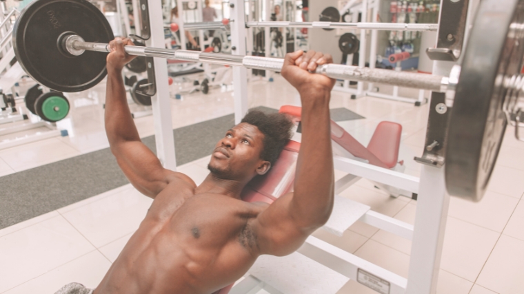 A person on the bench lifting a barbell up.