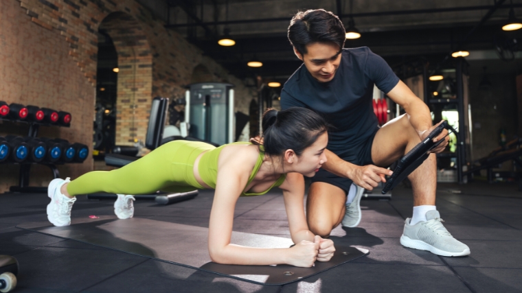 Person planning fitness program with mentor in the gym.