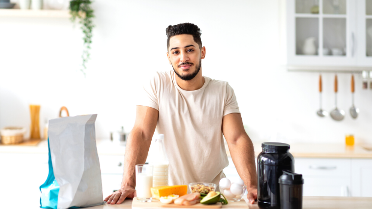A person with healthy food and protein powder on the table.