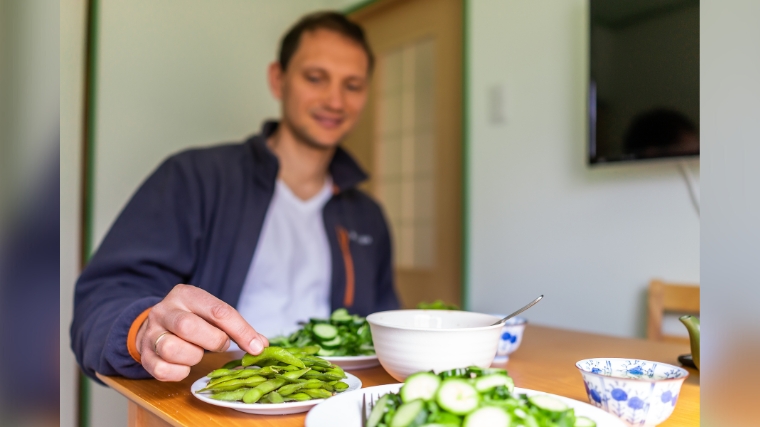 A person with with a plate of edamame on the table.