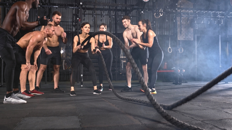 A person working out in a CrossFit box with other CrossFitters.