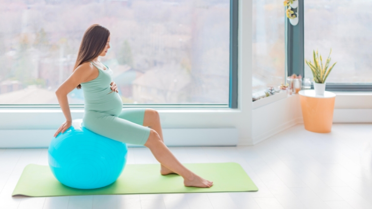 A pregnant person using a stability ball to exercise.