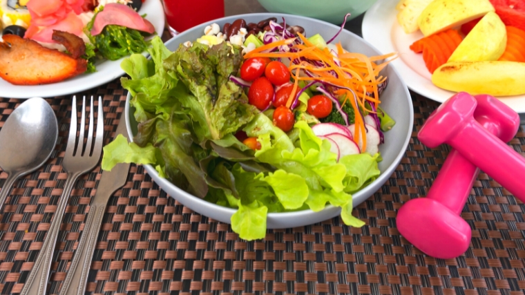 Hand weights and a salad on a table.