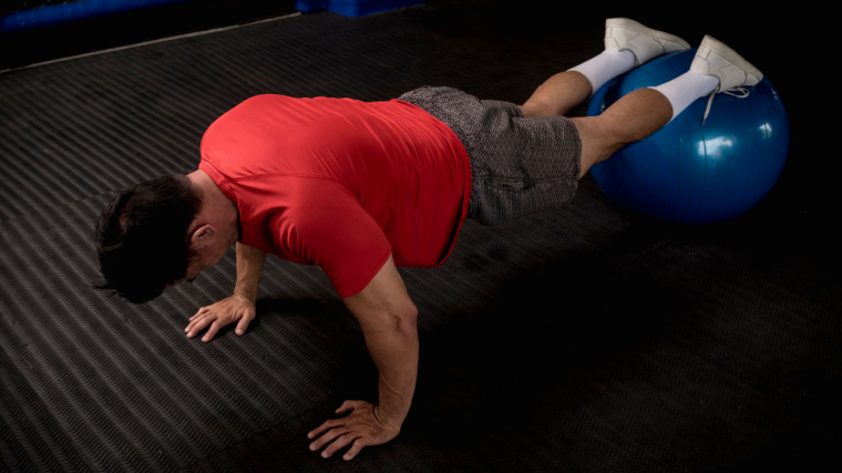 A person performs a push-up on a stability ball.