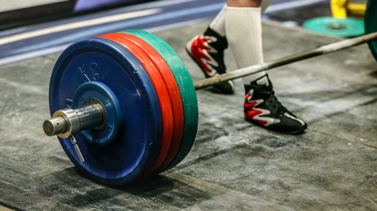 Weightlifter walking up to barbell loaded with bumper plates