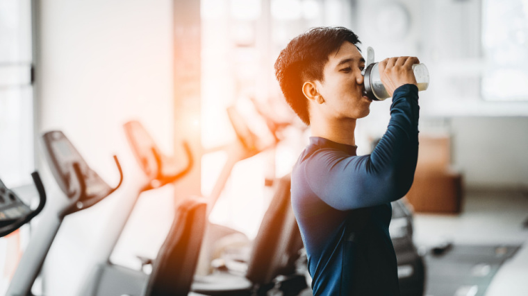 Person drinking from a shaker bottle in the gym