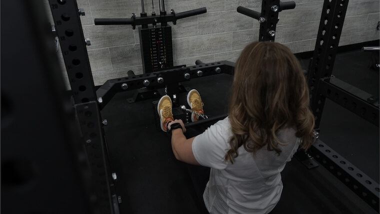 A person seated on the Bells of Steel Manticore Squat Cage.