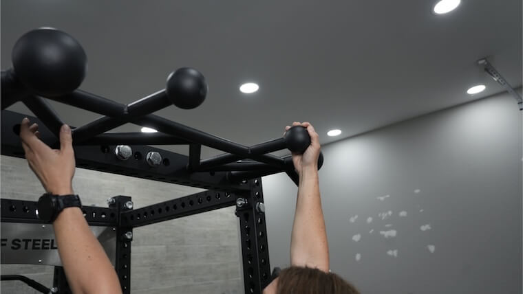 A person hanging from the Bells of Steel Manticore Squat Cage.