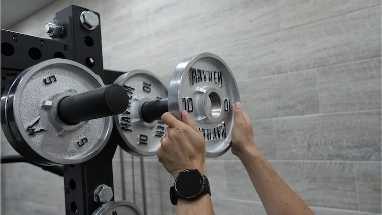 Loading weight plates onto the Bells of Steel Manticore Squat Cage.