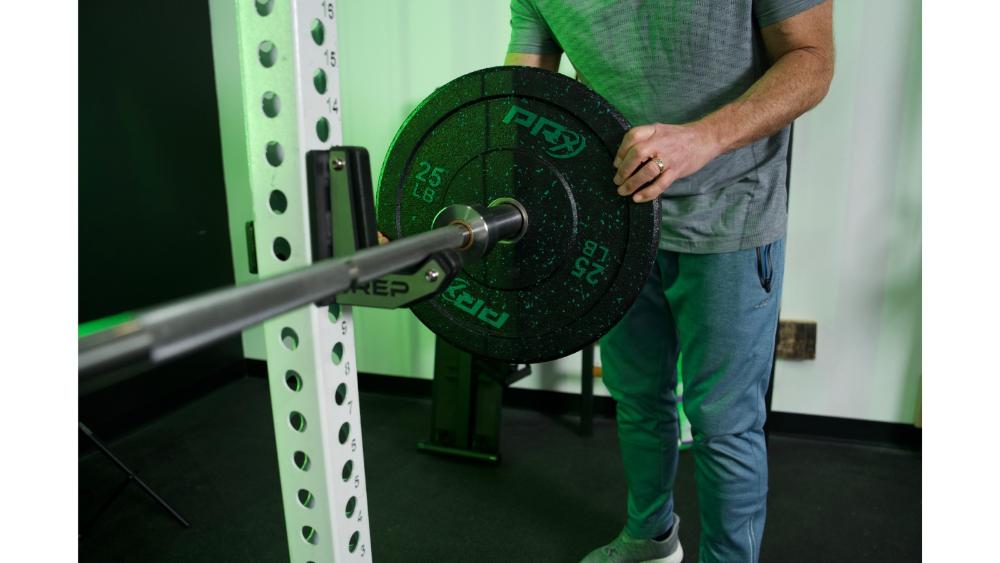 Loading PRx Crumb Rubber bumper plate on barbell