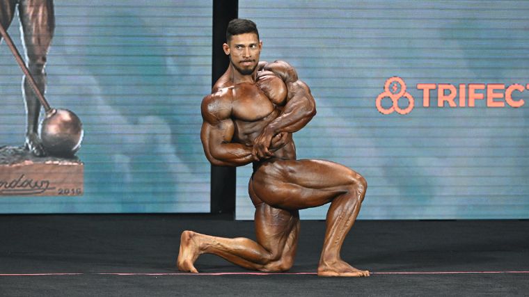 Classic Physique athlete Ramon Rocha Queiroz posing on stage at the 2022 Mr. Olympia.