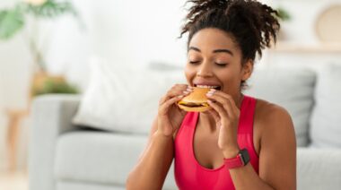 A gymgoer eating a burger on cheat day.