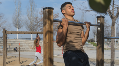 A person doing a chin-up in a park.