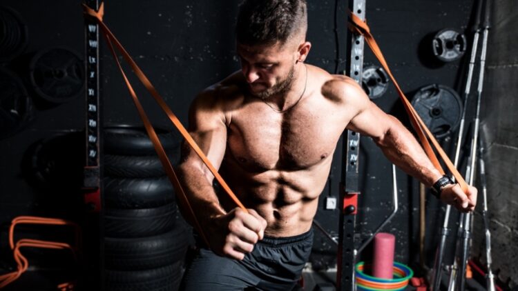 A muscular bodybuilder working out using resistance bands.