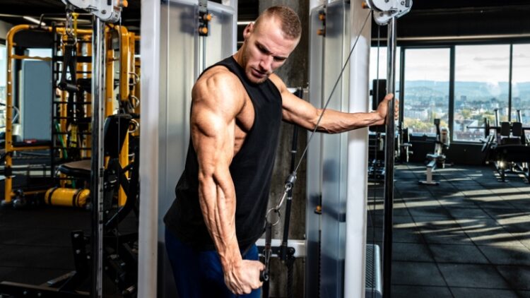 A person exercising his triceps using a cable machine.