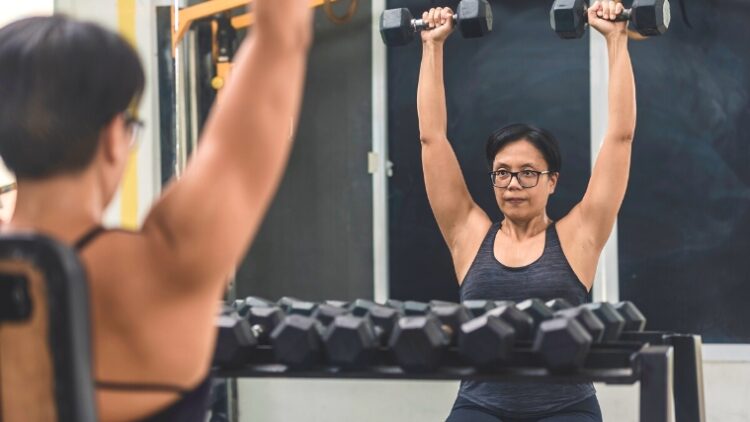 A person doing the dumbbell shoulder press.