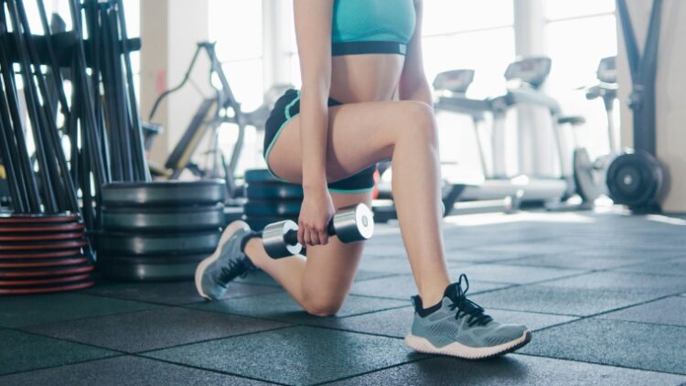 A person doing the dumbbell split squat with one knee touching the floor.