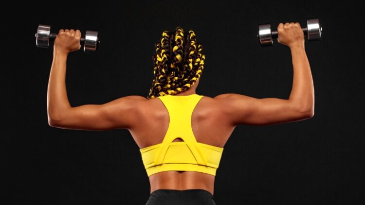 A person facing away and holding dumbbells over their shoulders.