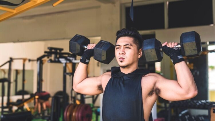 A person holding dumbbells over their shoulders.