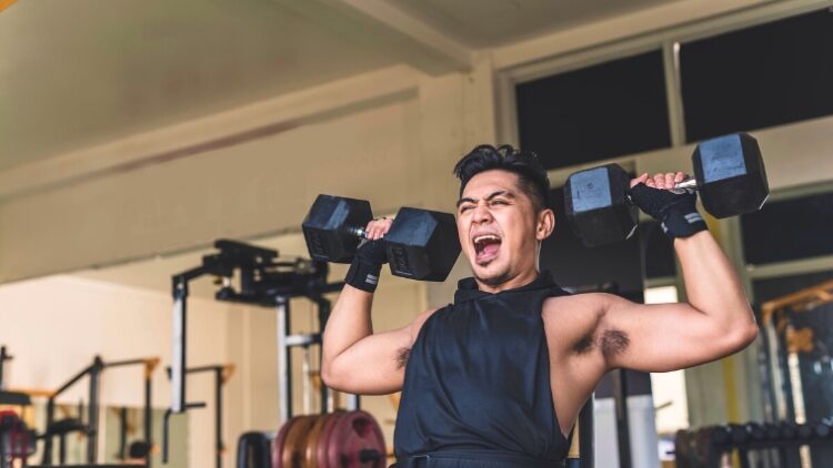 A person holding dumbbells over their shoulders back to starting position.