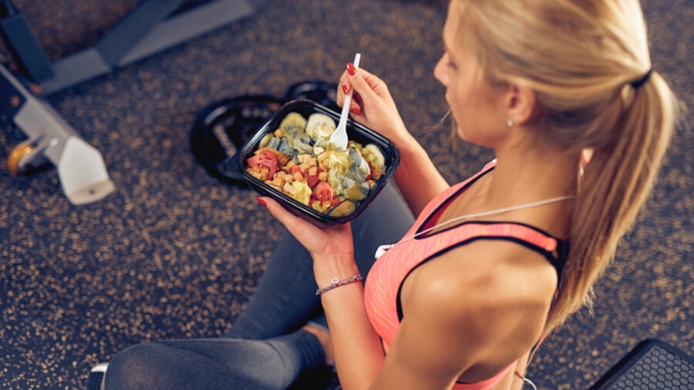 A person eating a salad in the gym