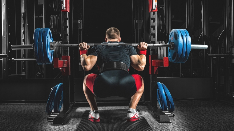 A person lifting a barbell off a rack.