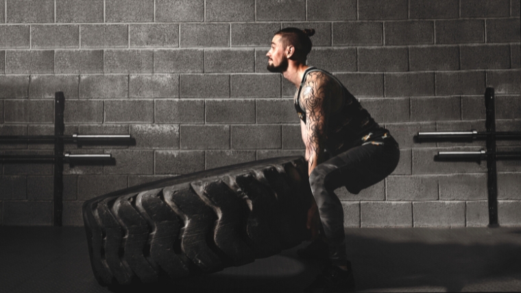 A person working out with a big tire.